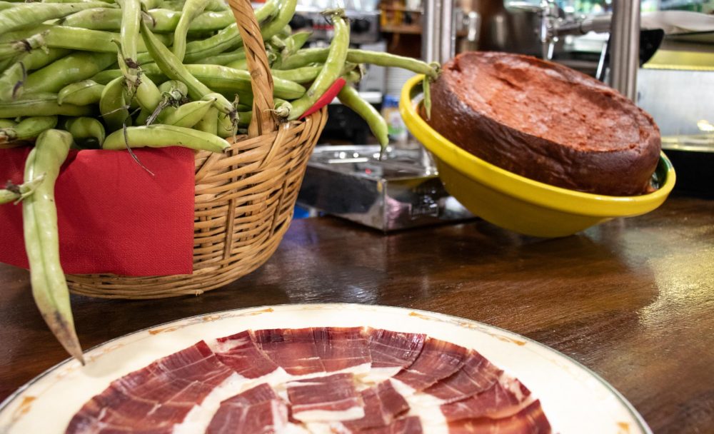 Cesta de habas, plato de jamón ibérico y sobrasada en barra de restaurante